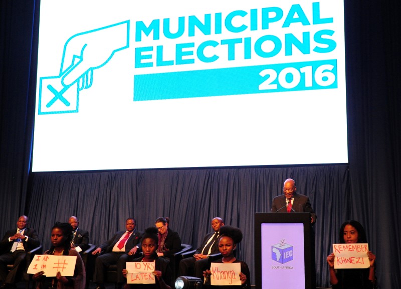South Africa's President Jacob Zuma (2nd R) makes a speech as protesters hold placards in front of him during the official announcement of the munincipal election results at the result centre in Pretoria, South Africa, August 6, 2016. REUTERS/Stringer