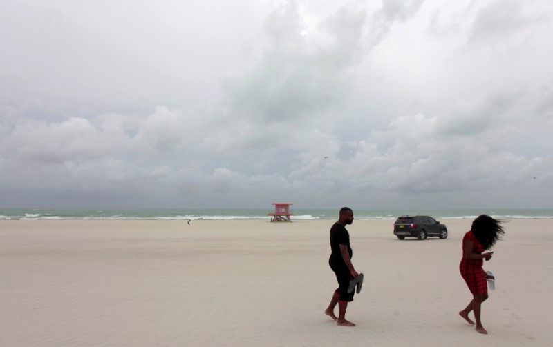 People walk along the beach prior to the arrival of Hurricane Matthew in Miami Beach, Florida, U.S. October 6, 2016. REUTERS/Javier Galeano
