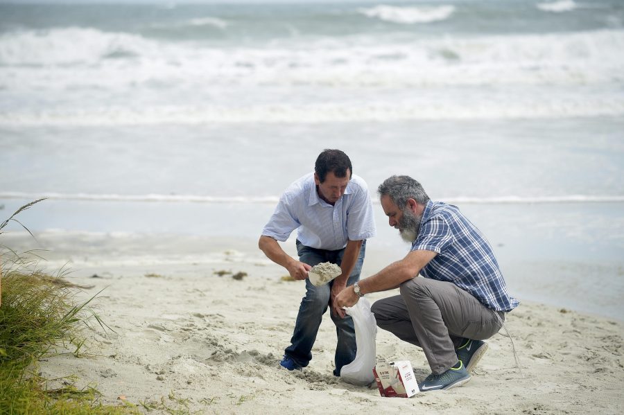 Bruno Cugianza, (L), and Gil Tal use trash bags to make sand bags on the beach before the arrival of Hurricane Matthew in Daytona Beach Shores, Florida, U.S., Oct. 6, 2016. REUTERS/Phelan Ebenhack