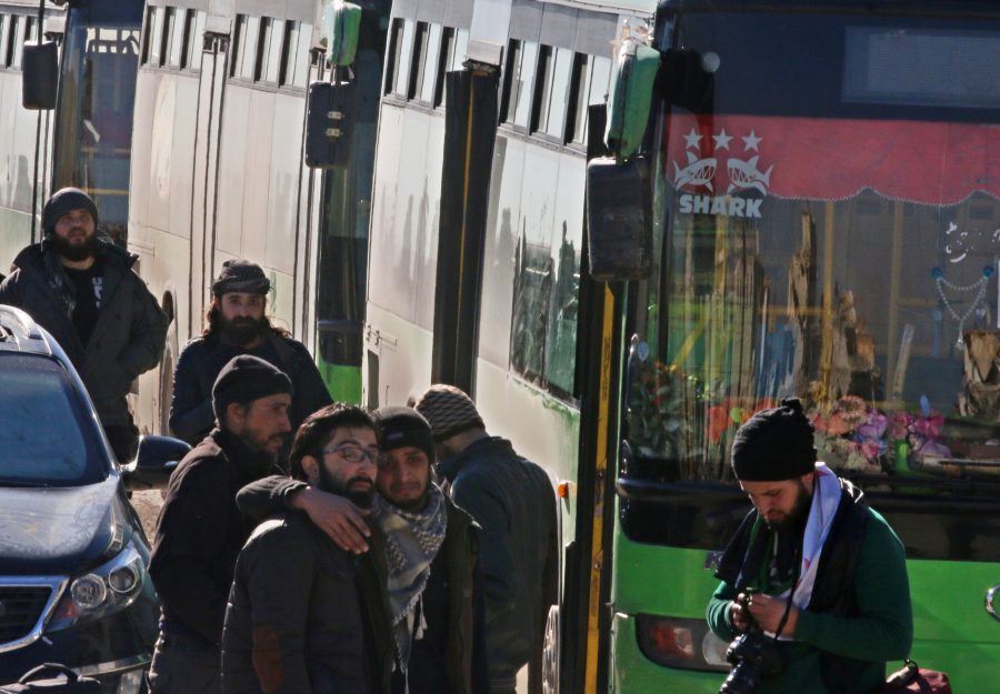 Men react as they stand outside buses evacuating people from a rebel-held sector of eastern Aleppo
