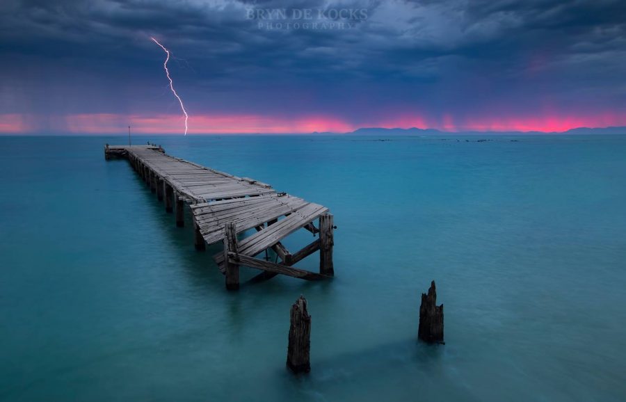 A Rich Red Glow On The Horizon With Single Lightning Strike Over Ocean And A Rich Red Glow On The Horizon With Single Lightning Strike Over Ocean And