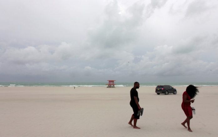 People walk along the beach prior to the arrival of Hurricane Matthew in Miami Beach