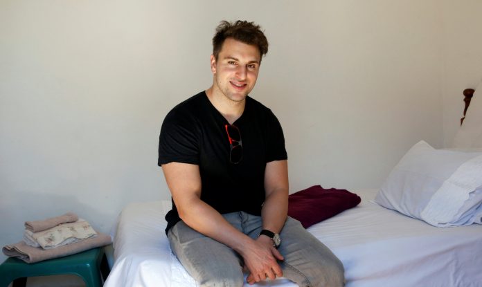 Co-founder and CEO of Airbnb Brian Chesky sits on a bed at a bed and breakfast in Langa township, Cape Town