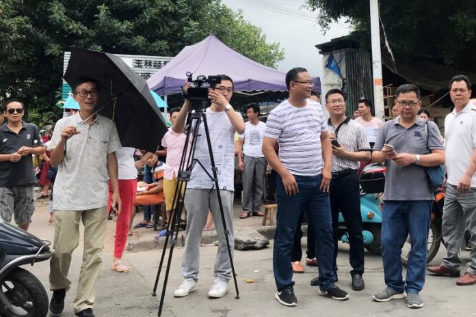 A cameraman is surrounded by local security guard outside a market during the local dog meat festival in Yulin