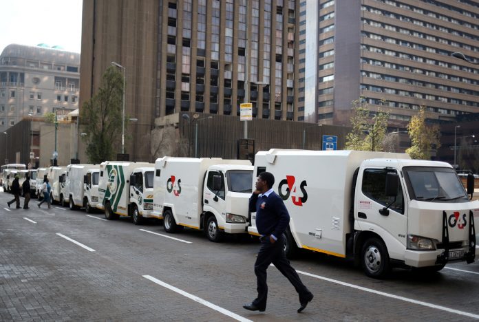 A cash-in-transit worker walks past armoured vehicles parked on the street during a nationwide protest following a spate of deadly heists this year, in Johannesburg cash in transit heists south africa