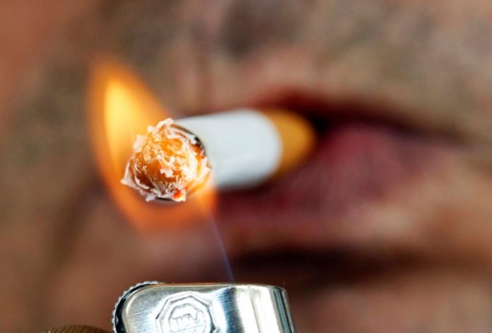 A man lights a cigarette on the street in Brioude