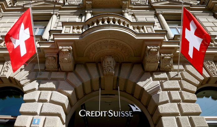 FILE PHOTO: Switzerland's national flags fly beside the logo of Swiss bank Credit Suisse in Zurich
