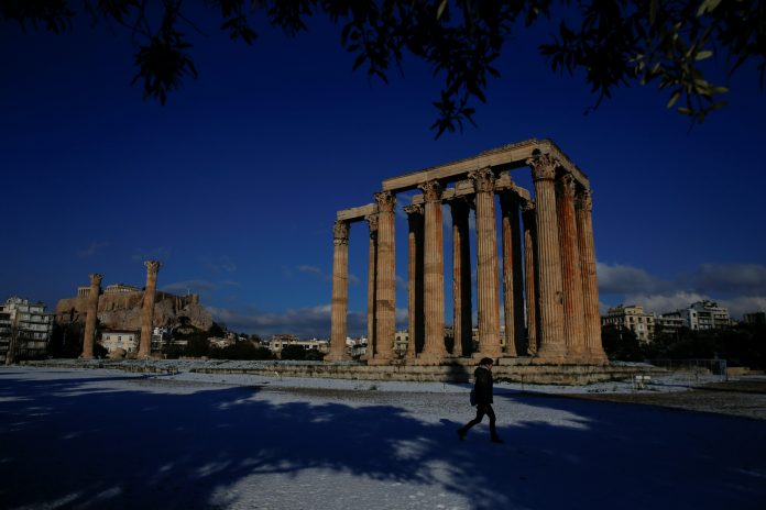 A visitor makes her way inside the archaeological site of the ancient Temple of Zeus following a snowfall in Athens