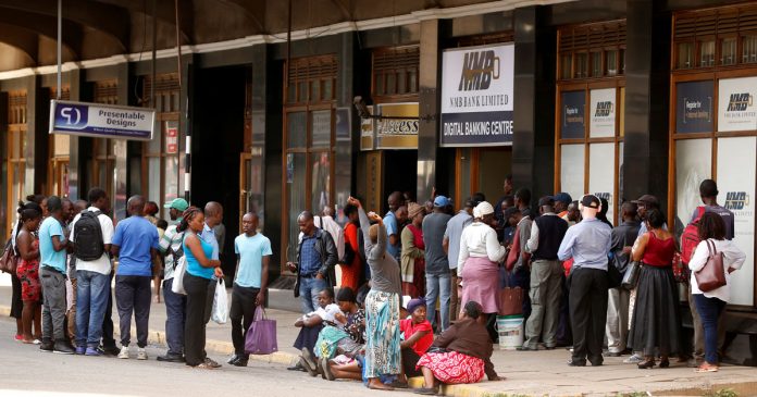 People queue to draw cash outside a bank in Harare