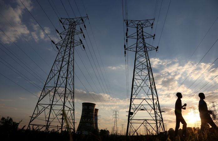 FILE PHOTO: Boys walk past electricity pylons and the cooling towers of the defunct Orlando Power Station in Soweto Eskom