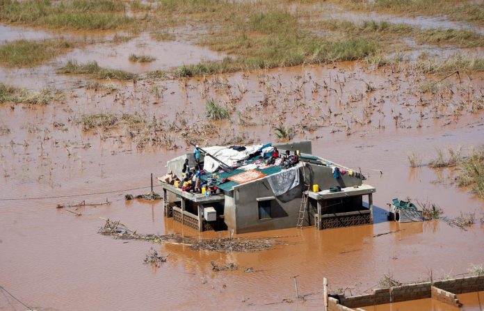 A stranded family sits on top of their home after Cyclone Idai