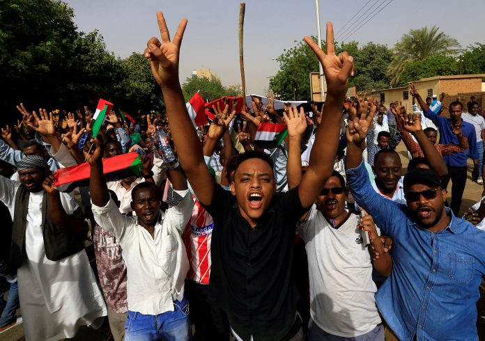 A Sudanese demonstrator flashes a two finger salute as they attend a protest rally demanding Sudanese President Omar Al-Bashir to step down outside the Defence Ministry in Khartoum