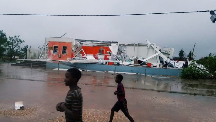 Children walk past a damaged building in the aftermath of the Cyclone Kenneth in Pemba