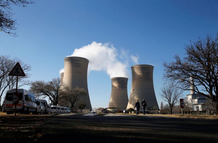 Workers are seen near cooling towers of the Hendrina power station, located south of Middelburg