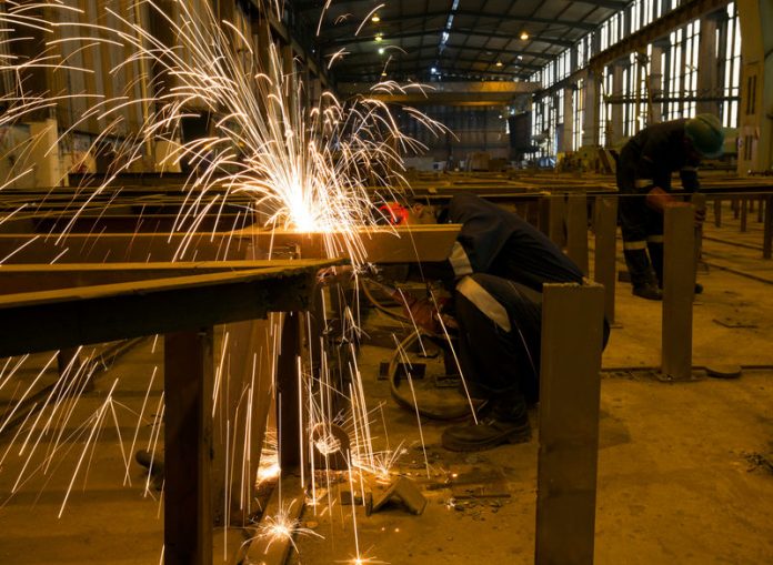 A worker cuts steel at the Southern African Shipyards where a tug for the state owned enterprise Portnet is under construction in Durban