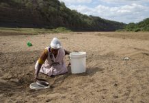 A woman gets water from a well dug in the Black Imfolozi River bed, which is dry due to drought, near Ulundi