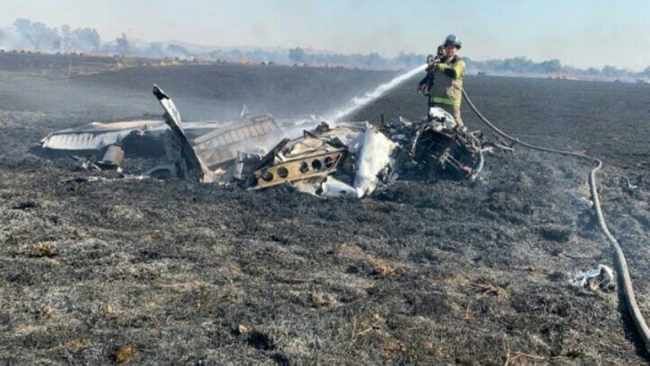 A firefighter douses down the wreckage of the plane in which rookie pilot Anika de Beer, 16, died while she was flying solo