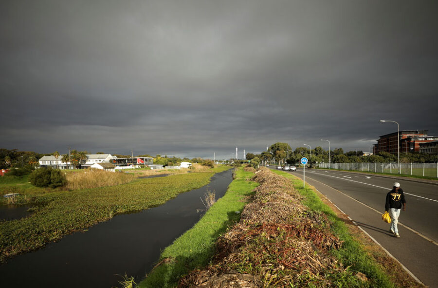 A man walks past contested land earmarked for a development which includes a new Africa headquarters for U.S. retail giant Amazon, alongside the Liesbeek river in Cape Town, South Africa June 2, 2021. Picture taken June 2, 2021. REUTERS/Mike Hutchings