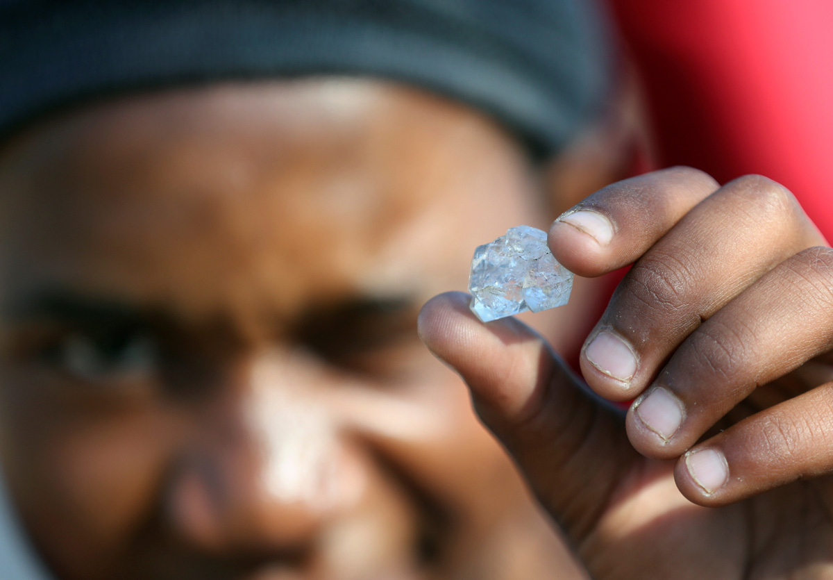 A man shows an unidentified stone as fortune seekers flock to the village after pictures and videos were shared on social media showing people celebrating after finding what they believe to be diamonds, in the village of KwaHlathi outside Ladysmith, in KwaZulu-Natal province, South Africa, June 14, 2021. REUTERS/Siphiwe Sibeko