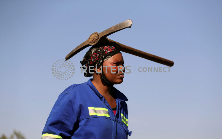A woman arrives carrying a pickaxe on her head as fortune seekers are flocking to the village after pictures and videos were shared on social media showing people celebrating after finding what they believe to be diamonds, in the village of KwaHlathi outside Ladysmith, in KwaZulu-Natal province, South Africa, June 14, 2021. REUTERS/Siphiwe Sibeko