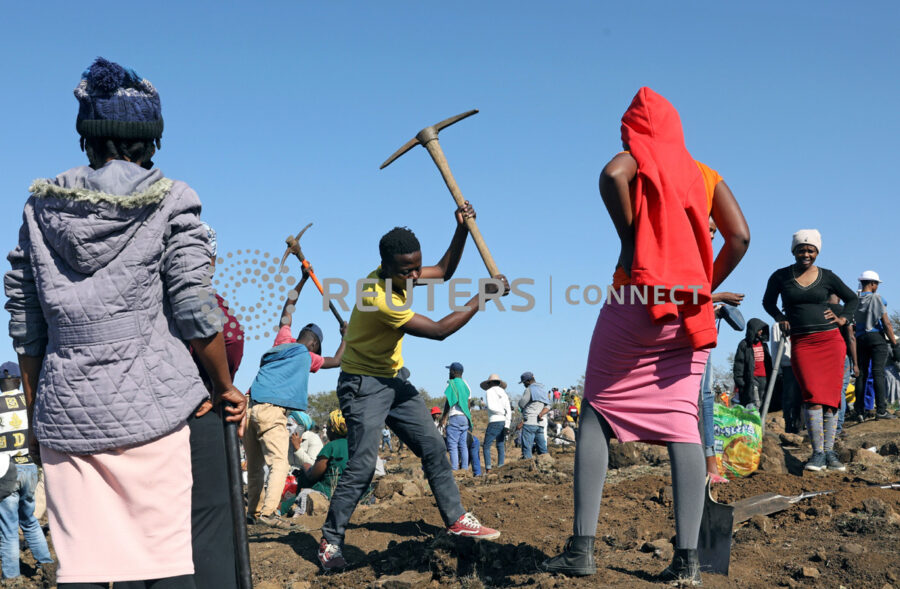 A man uses a pickaxe to dig as fortune seekers flock to the village after pictures and videos were shared on social media showing people celebrating after finding what they believe to be diamonds, in the village of KwaHlathi outside Ladysmith, in KwaZulu-Natal province, South Africa, June 14, 2021. REUTERS/Siphiwe Sibeko