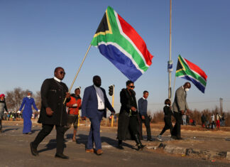 Religious leaders carrying South African flags walk near a looted shopping mall as the country deploys army to quell unrest linked to the jailing of former South African President Jacob Zuma, in Vosloorus, South Africa, July 14, 2021. REUTERS/Siphiwe Sibeko