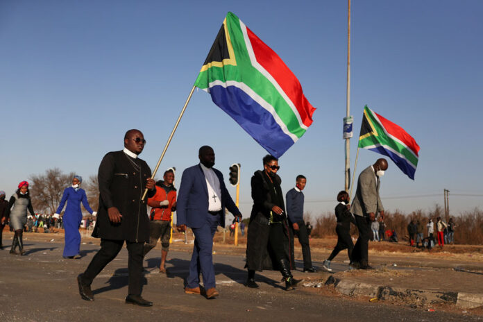 Unrest linked to the jailing of former South African President Zuma, in Vosloorus Religious leaders carrying South African flags walk near a looted shopping mall as the country deploys army to quell unrest linked to the jailing of former South African President Jacob Zuma, in Vosloorus, South Africa, July 14, 2021. REUTERS/Siphiwe Sibeko