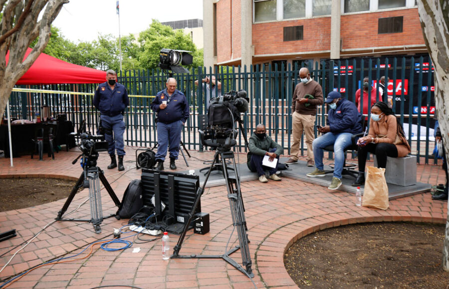 Policemen and news reporters look at a monitor as former South African president Jacob Zuma appears in the High Court in Pietermaritzburg