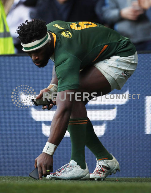 Siya Kolisi picks up mobile phones from the pitch before taking selfies with fans after the match Action Images via Reuters/Lee Smith