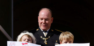 Prince Albert II of Monaco, Prince Jacques and Princess Gabriella holding message which read "We miss you mommy" and "We love you mommy", stand on the palace balcony during the celebrations marking Monaco's National Day in Monaco, November 19, 2021. REUTERS/Eric Gaillard