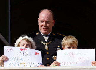 Prince Albert II of Monaco, Prince Jacques and Princess Gabriella holding message which read "We miss you mommy" and "We love you mommy", stand on the palace balcony during the celebrations marking Monaco's National Day in Monaco, November 19, 2021. REUTERS/Eric Gaillard