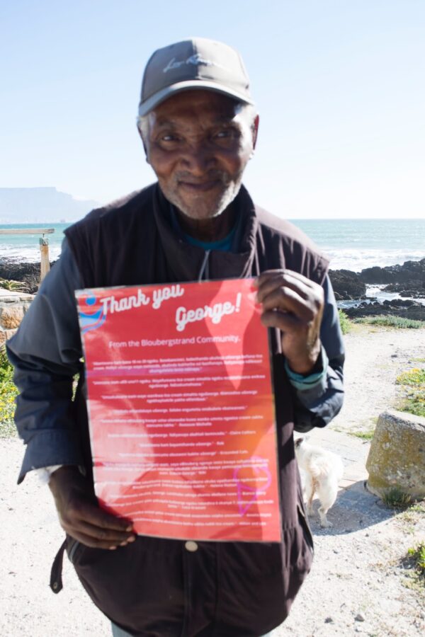 George proudly holds a sign with all his donation messages