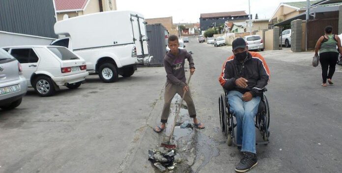 wheelchair man cleans streets John Martin and Shiloh Felix go out together to collect rubbish in their street in Gqeberha. Photo: Joseph Chirume