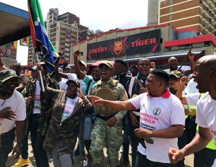 People attending an Operation Dudula protest wear branded T-shirts, which were on sale for R50. Nhlanhla Lux Dlamini, one of the group’s leaders, was among a handful of people wearing military-style clothing. Dlamini said they would not rest until South Africans were put first and given more opportunities. Photo: Masego Mafata People attending an Operation Dudula protest wear branded T-shirts, which were on sale for R50. Nhlanhla Lux Dlamini, one of the group’s leaders, was among a handful of people wearing military-style clothing. Dlamini said they would not rest until South Africans were put first and given more opportunities. Photo: Masego Mafata