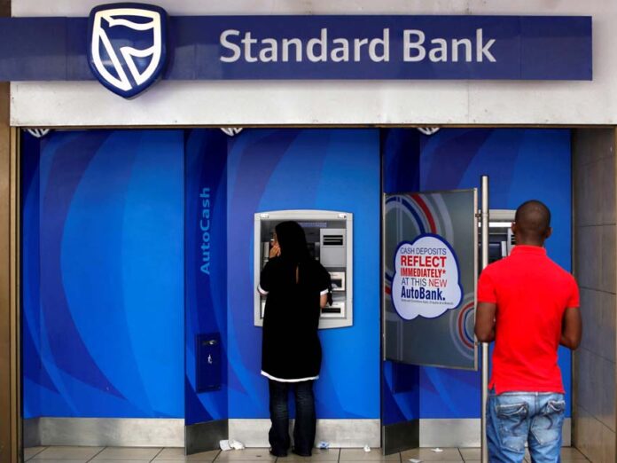 FILE PHOTO: Customers queue to draw money from an ATM outside a branch of South Africa's Standard Bank in Cape Town Standard Bank Bans Financing New Coal-Fired Plants in Aim for Net Zero by 2050, Activists Press for More