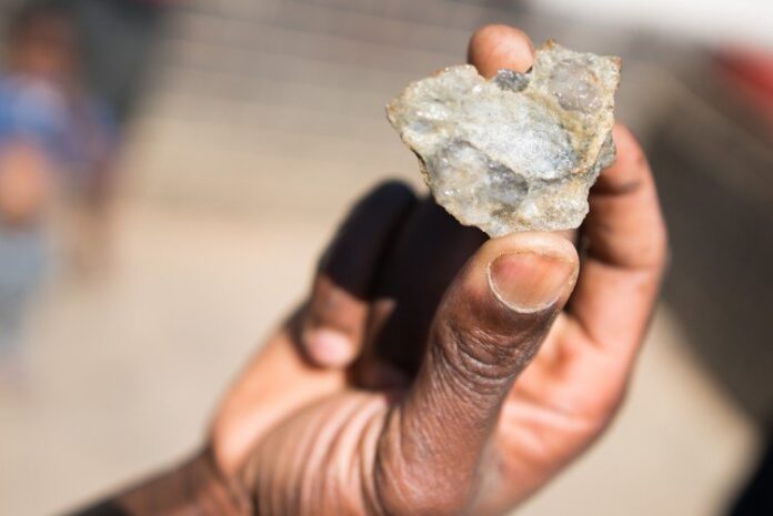 An informal miner holds up a piece of rock containing flecks of gold. Archive photo: Shaun Swingler