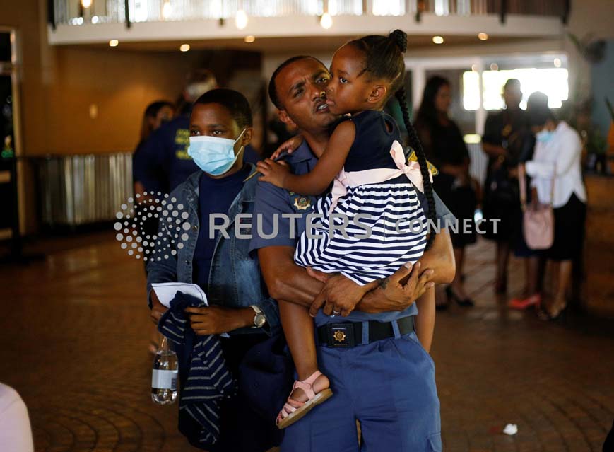 Sergeant Jesse Mare holds Aphelele Mjwara, the daughter of his colleague police diver Sergeant Busisiwe Mjwara who died while searching for flood victims, at her memorial service in Pietermaritzburg