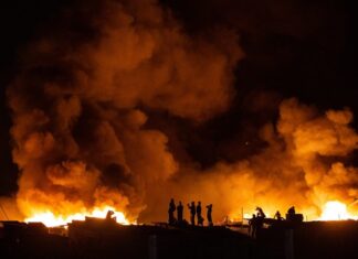 People watch their neighbourhood engulfed in flames.