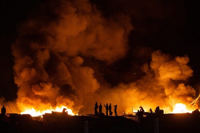 People watch their neighbourhood engulfed in flames.