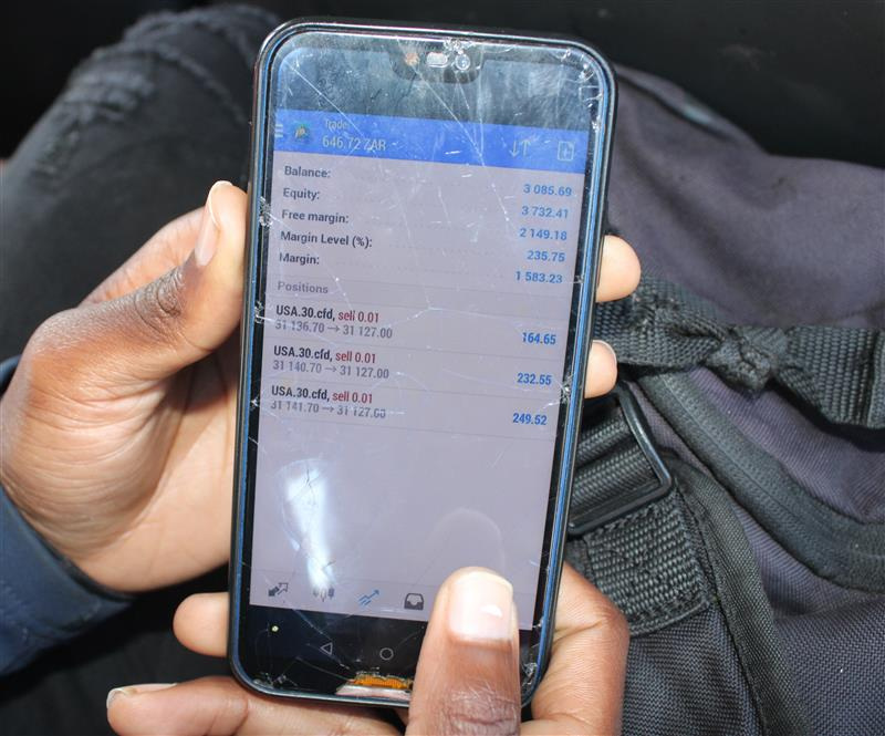 A young man shows his cryptocurrency trades on his mobile phone in Tsakane Township, South Africa. August 21, 2022. Thomson Reuters Foundation/Kimberly Mutandiro