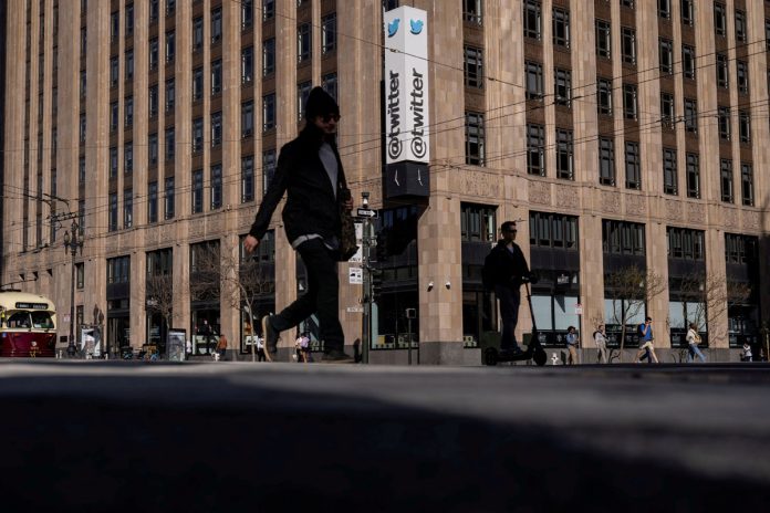 FILE PHOTO: People walk by a Twitter logo at the company headquarters in downtown San Francisco, California