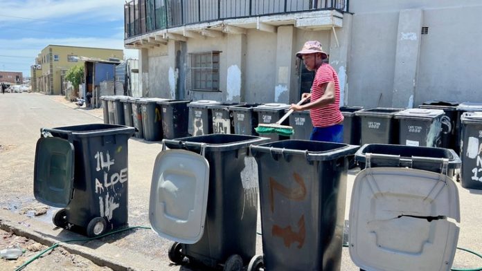 Siyanda Nohashe cleans municipal wheelie bins along Aloe Street in Dunoon. He supports himself and pays one permanent and one casual worker. Photo: Peter Luhanga Siyanda Nohashe cleans municipal wheelie bins along Aloe Street in Dunoon. He supports himself and pays one permanent and one casual worker. Photo: Peter Luhanga