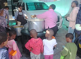 Phathiswa Madyongolo and Noholide Ngcongca serve food to Pheliswa Ngubo at the soup kitchen in Mfuleni. Photos: Masixole Feni