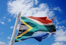 29 years of democracy has left its mark. Rather battered and frayed South African flag billowing in the wind against a cloud-strewn sky.