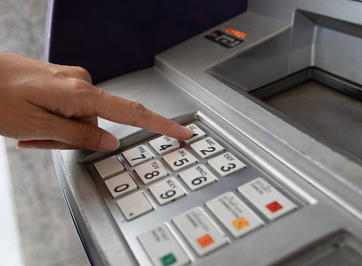 fingers using an ATM. This image accompanies an article titled 'Major South African bank Capitec hit with R28 million Reserve Bank fine'